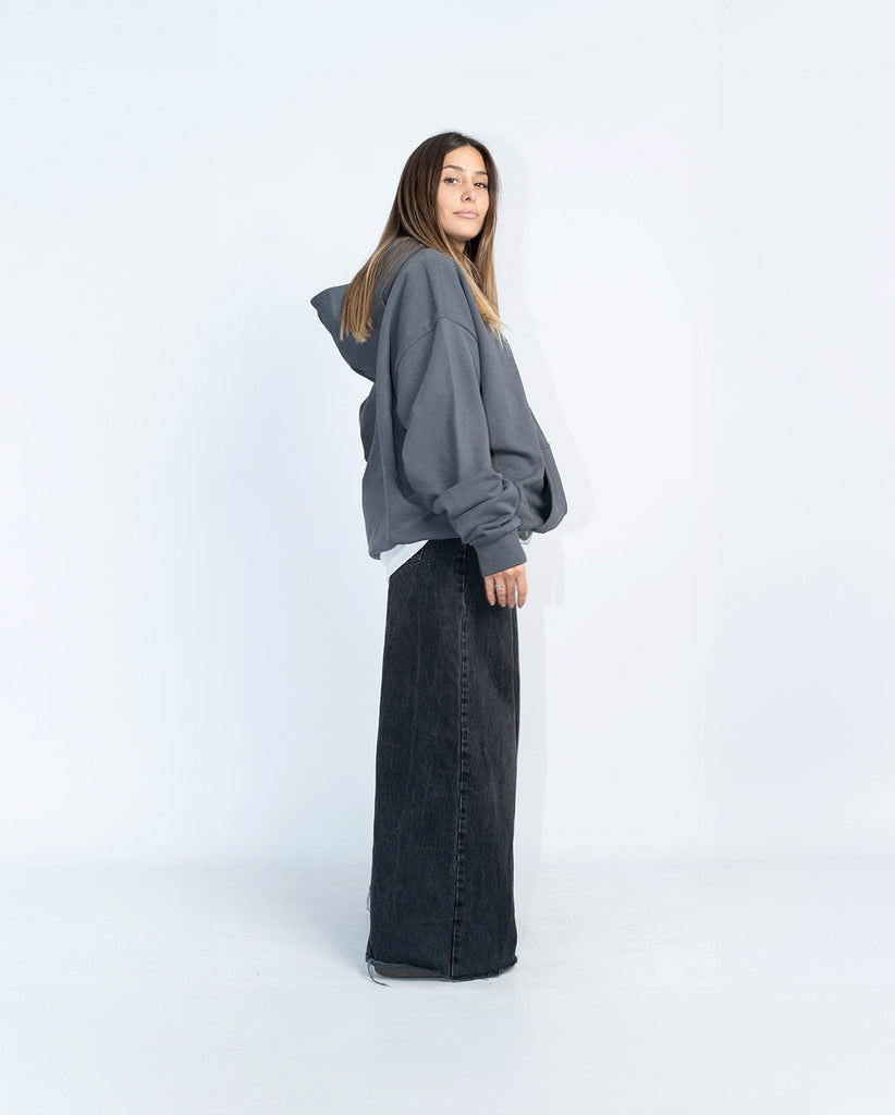 Modelo femenina vistiendo la sudadera gris oversize con bordado 3D gris, vista trasera.