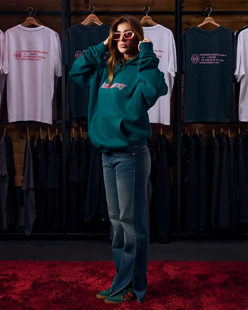 Modelo femenina vistiendo la sudadera verde oversize con bordado 3D rosa, vista frontal.